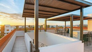 Una terrassa al terrat amb una piscina, mobiliari exterior i vista a la ciutat.