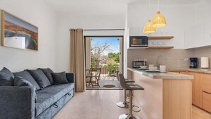 A modern living room with a sofa, a dining area, and a kitchen with a view. - Pineda Suite 202 with Parking (La Paz)