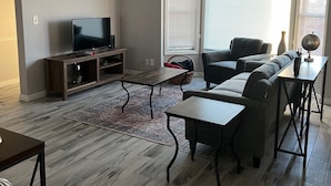 Sala de estar con televisor, sofá y mesa de centro.