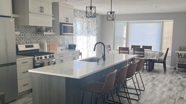 Una cocina moderna con una isla grande, taburetes de bar y un comedor con mesa y sillas.