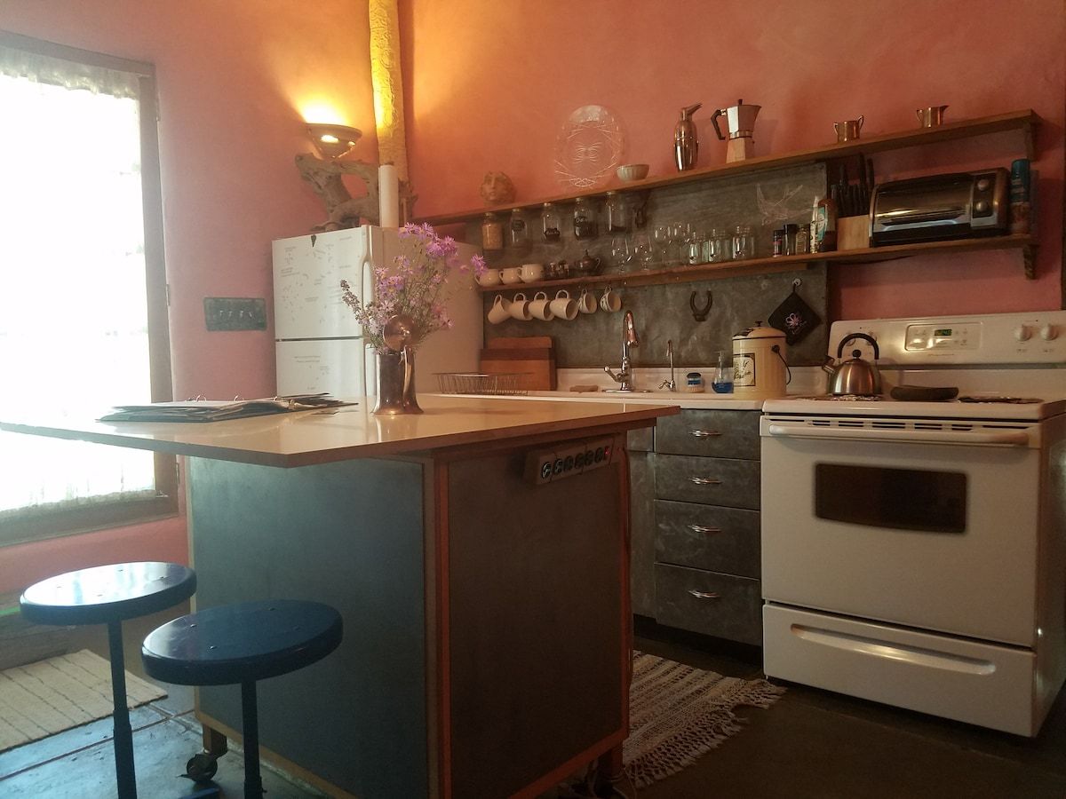 A compact kitchen with a refrigerator, oven, and a small bar area with stools.