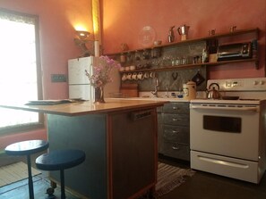 Une cuisine compacte équipée d’un réfrigérateur, d’un four et d’un petit coin bar avec des tabourets.