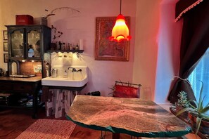 Cozinha com mesa de madeira, pia e luminária pendente.