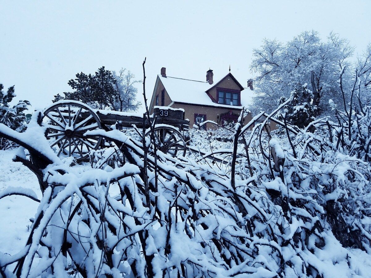 A snow-covered landscape with a house and a wooden cart in the foreground.