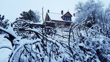 A snow-covered landscape with a house and a wooden cart in the foreground.