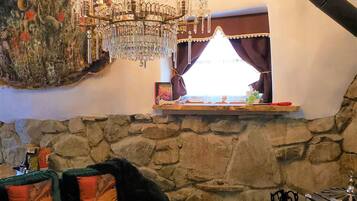 A cozy living room with a stone wall, a chandelier, a fireplace, and a sofa with cushions.