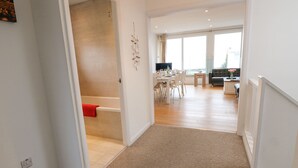 A modern interior with a hallway leading to a dining area and a living space. - Sea House (Littlehampton)