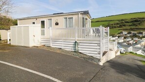 A mobile home with a fenced deck and a view of a green field.