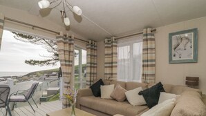 A cozy living room with a sofa, a coffee table, and a view of the sea. - Ocean Pearl (Kingsbridge)