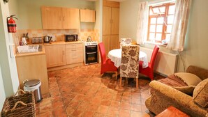 A compact kitchen with basic appliances, a dining area with a table and chairs, and a cozy living space with a sofa. - Ratty's Retreat (Spilsby)