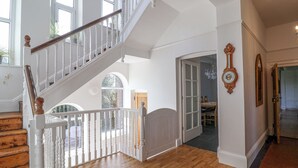 Un interior espacioso con una escalera de madera, un comedor y vistas al exterior.