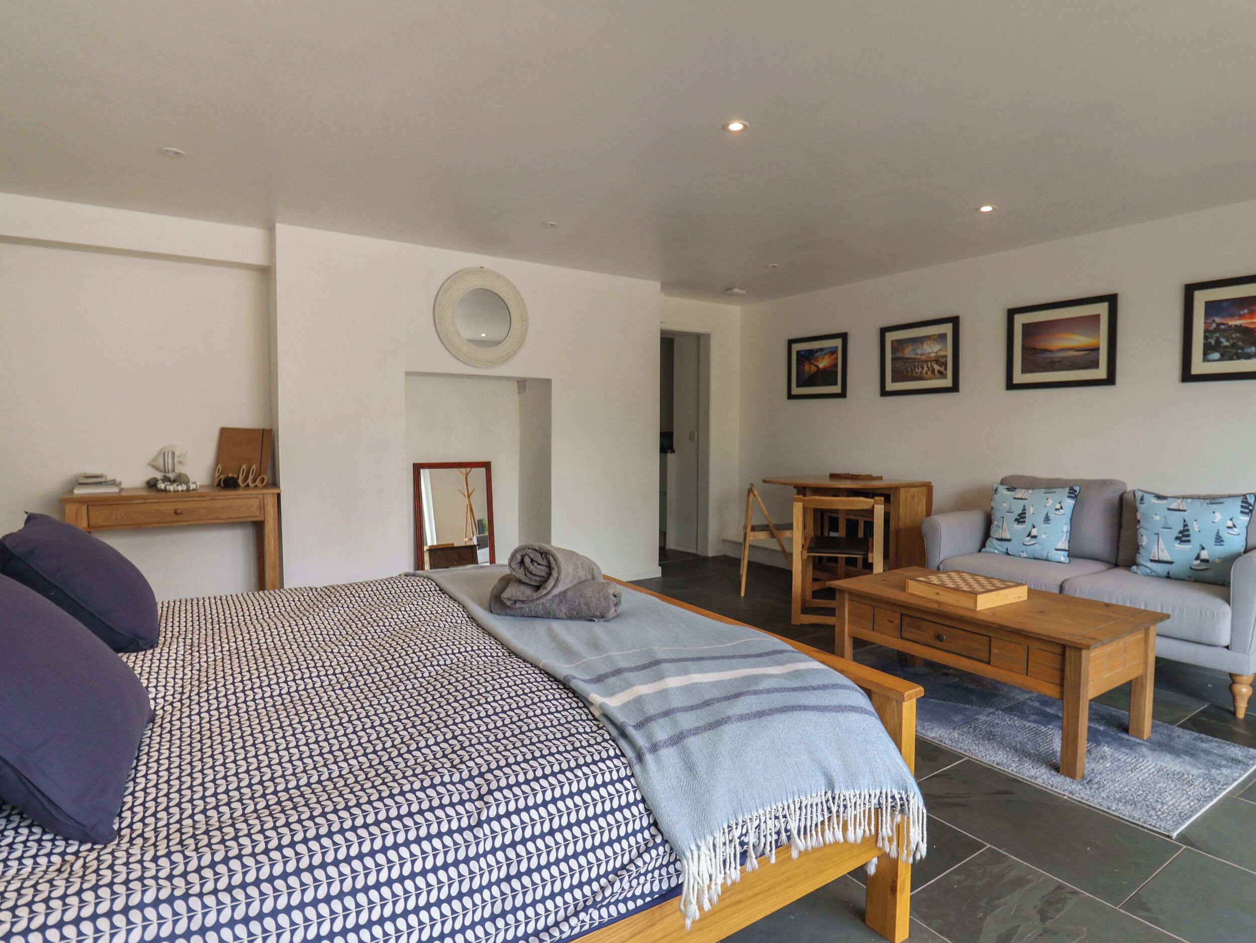 A modern bedroom with a bed, bedside table, and a view into the living area.