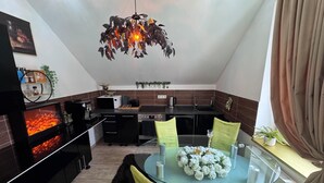 A modern kitchen with a glass dining table, black cabinets, and a unique leaf-shaped pendant light.
