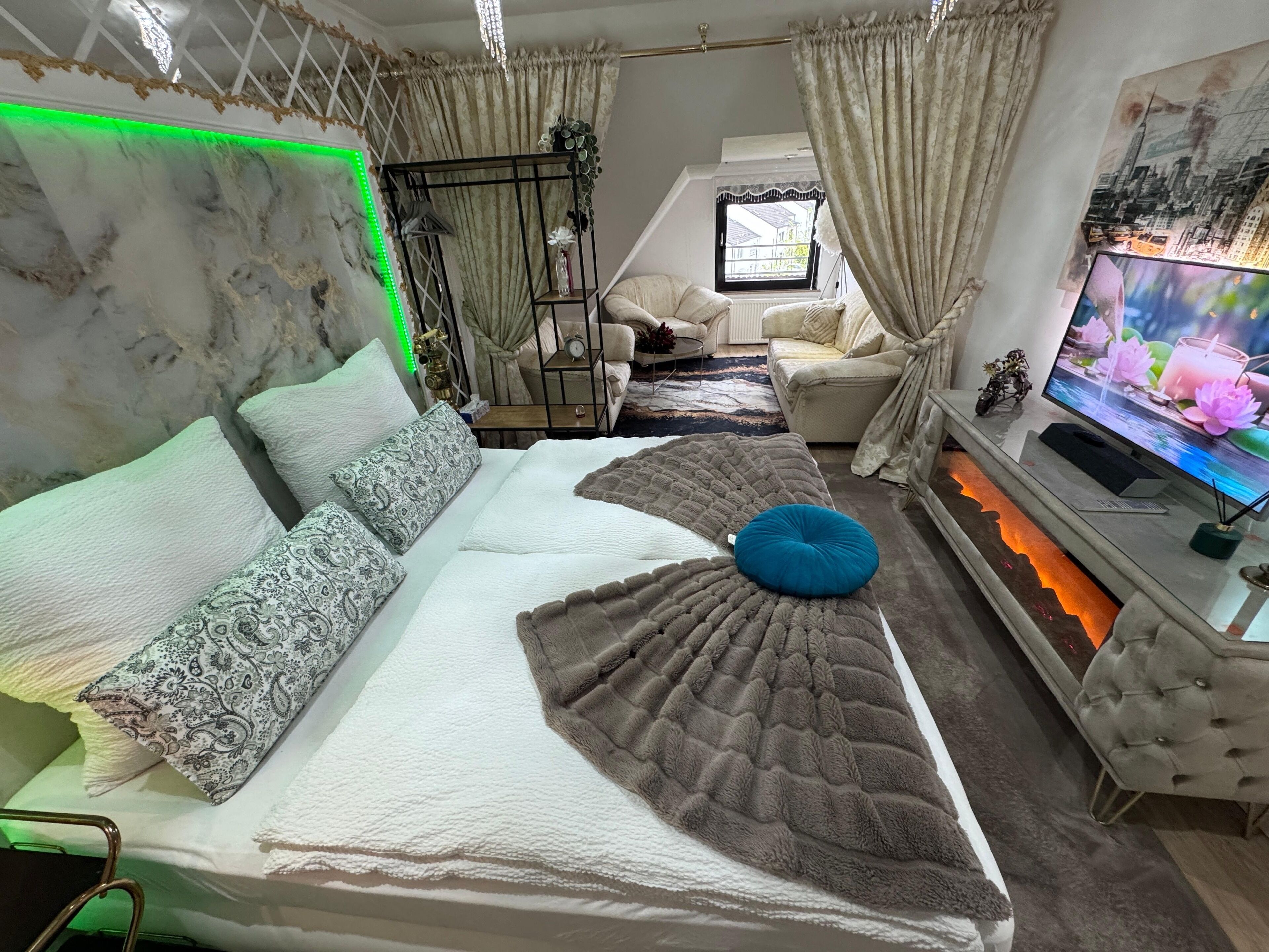 A bedroom with a bed, a TV, and a window.