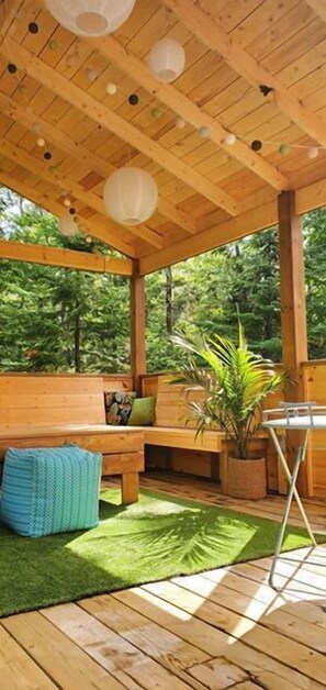 Una terraza de madera con un banco, una mesa y una planta en maceta.
