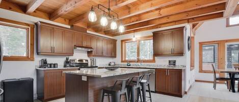 A kitchen with wooden cabinets, a central island with stools, and pendant lighting.