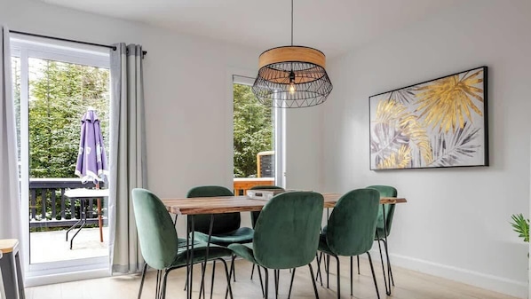 A dining area with a wooden table, green chairs, a pendant light, and a framed artwork on the wall. - Apollon - Family Paradise - Pool, Spa, Sauna (Pont-Rouge)