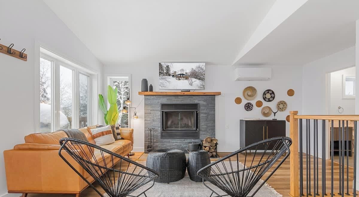 Una sala de estar moderna con chimenea, un sofá y dos sillones.