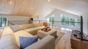 Un salon moderne avec un grand canapé d’angle, une table basse et un téléviseur.