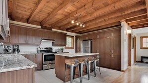 Une cuisine moderne avec des meubles en bois, des appareils en acier inoxydable et un îlot central doté de tabourets de bar.