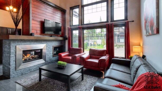 A modern living room with a fireplace, leather sofas, and large windows. - Chalet charmant Vacances avec Spa by Alchalet (Scott)