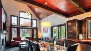 A spacious dining area with a high ceiling, large windows, and a fireplace. - Chalet charmant Vacances avec Spa by Alchalet (Scott)