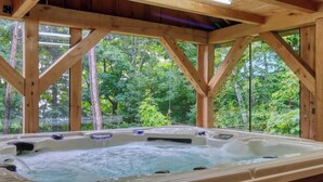 A wooden hot tub with a view of a forest.