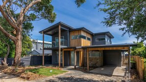 Une maison moderne à deux étages, dotée d’un grand garage, d’un patio couvert et d’une cour bien entretenue.