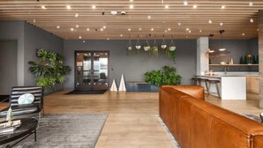 A modern interior with a wooden ceiling, seating area, and a kitchen. - Jazzy Blue at HYVE | Near Gulch & Broadway (Nashville)