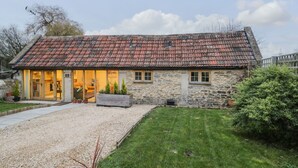 A stone building with a tiled roof, a gravel driveway, and a well-maintained lawn.