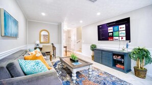 A modern living room with a sofa, coffee table, and a flat-screen TV displaying streaming services.