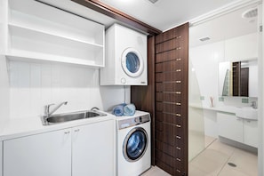 A modern bathroom with a built-in washing machine, a sink, and a mirror.