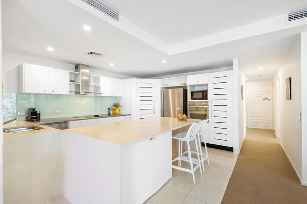 A modern kitchen with white cabinetry, a central island, and stainless steel appliances.