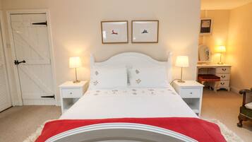A bedroom with a white bed, two bedside lamps, a dresser, and a door with a barn-style design.