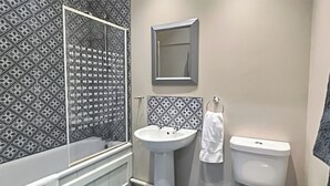 A bathroom with a bathtub, sink, and toilet. - 1 bedroom accommodation in Adversane, near Billingshurst (Adversane, near Billingshurst)