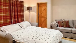 A bedroom with a bed, a sofa, a lamp, and a wooden door. - 1 bedroom accommodation in Adversane, near Billingshurst (Adversane, near Billingshurst)