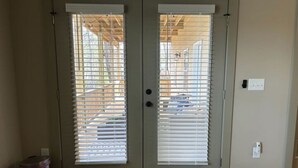 A double door with a metal handle and a keyhole, a trash can, and a power outlet on the wall. - Choctaw Ridge King Bed-Private Deck-Gas Firepit (Dahlonega)