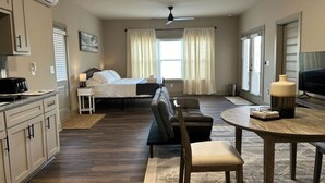 A hotel room with a bed, a sofa, a dining table, a TV, and a kitchenette. - Choctaw Ridge King Bed-Private Deck-Gas Firepit (Dahlonega)
