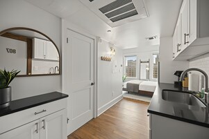 Una cocina moderna con armarios blancos, encimera negra y suelo de madera.