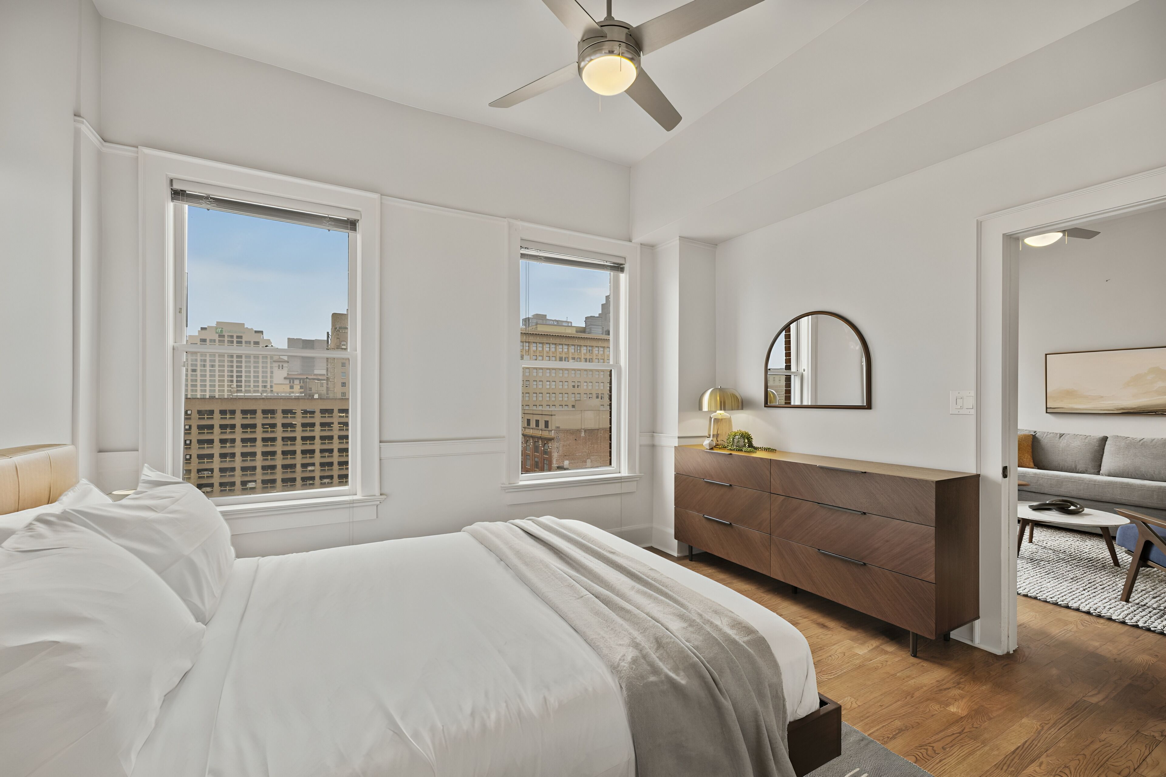 A bedroom with a bed, dresser, and a ceiling fan.