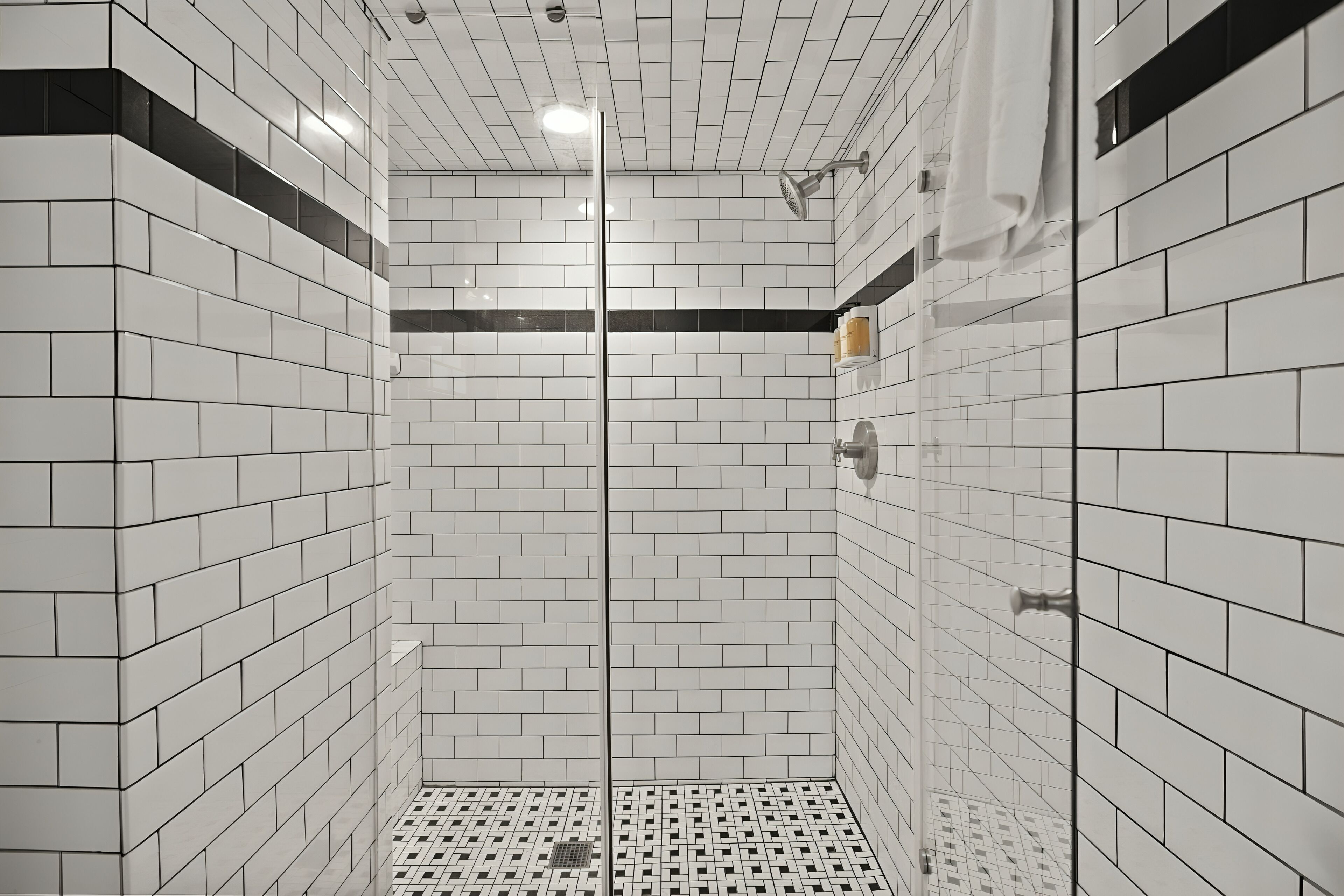 A modern bathroom with white subway tiles, a glass shower enclosure, and a tiled floor.