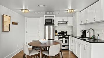 A modern kitchen with white cabinetry, stainless steel appliances, and a black countertop.