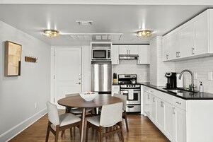 A modern kitchen with white cabinetry, stainless steel appliances, and a black countertop.