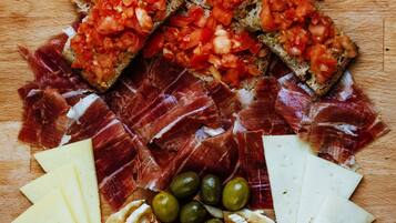Una tabla de madera con diversos alimentos, incluyendo pan, queso, aceitunas y embutidos.
