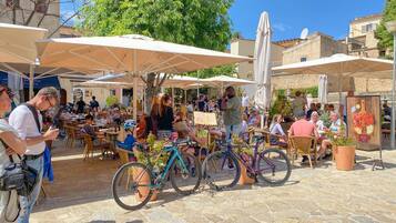 Un café al aire libre con suelo de piedra, sombrillas y bicicletas.