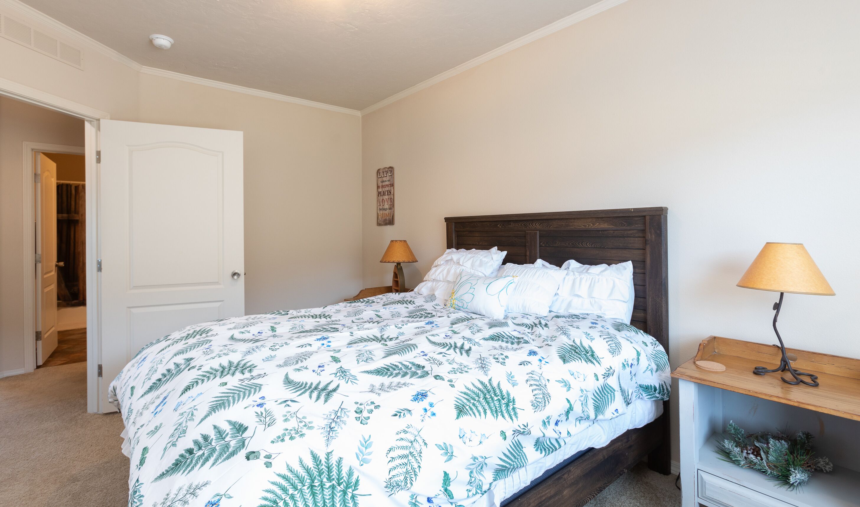 Een slaapkamer met een bed, nachtlampjes, een deur en een decoratie aan de muur.