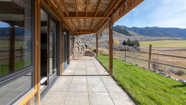 A covered outdoor area with a stone pathway leading to a building with large windows.