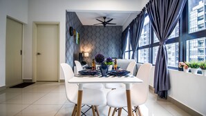 A modern dining area with a white table, four white chairs, a ceiling fan, and a view of buildings through large windows. - Arte plus KLCC By Tenang Home (Kuala Lumpur)