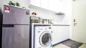 A compact kitchen with a stainless steel refrigerator, a washing machine, and a microwave. - Arte plus KLCC By Tenang Home (Kuala Lumpur)
