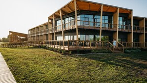 Un edificio moderno con varios pisos, ventanas amplias y una zona con terraza de madera.